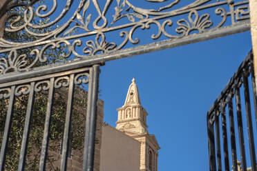 Malta, Northern Region, Mellieha, Bell tower of Parish Church of Nativity of Virgin Mary seen through open gate - TAMF03107