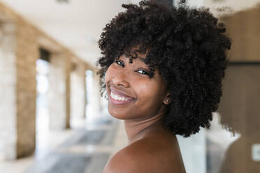 Smiling Afro woman looking over shoulder - JRVF01108