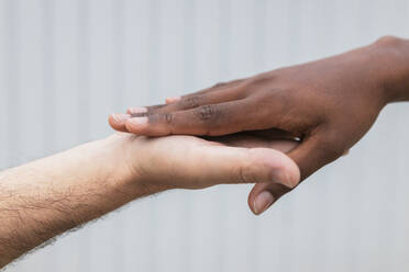 Woman and man touching hands by wall - JRVF01119