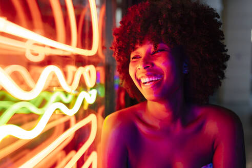 Glückliche junge Frau mit Blick auf Neonlichter - JRVF01142