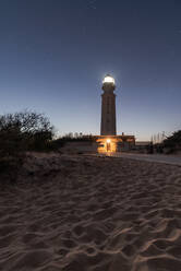 Lighthouse with bright lights placed on sandy beach in Faro de Trafalgar in Cadiz in Spain under night sky with stars - ADSF24855
