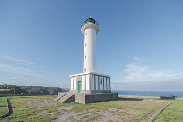 Asphaltstraße zum weißen Leuchtturm in Faro de Lastres in Asturien in Spanien unter wolkenlosem blauen Himmel bei Tag - ADSF24862