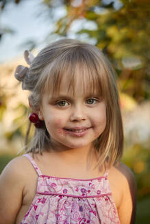 Cute blond girl with messy mouth smiling in backyard - ZEDF04252