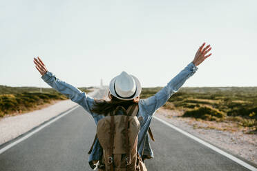 Carefree woman with arms outstretched standing on road - EBBF04049