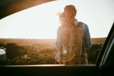 Female backpacker seen from car window during sunset - EBBF04058