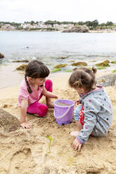 Schwestern spielen mit Sand am Strand während der Ferien - GEMF04871