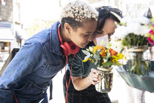 Lesbisches Paar riecht an Blumen auf dem Straßenmarkt - PMF01825