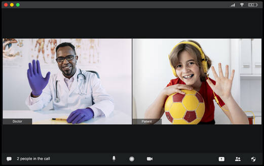 Happy little boy in headphones with ball in hand and young African American male doctor greeting each other with hand gesture while having video chat during online consultation - ADSF25020