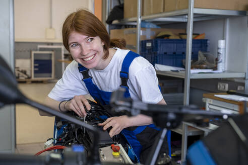 Lächelnde Technikerin, die bei der Arbeit in der Werkstatt wegschaut - LBF03525