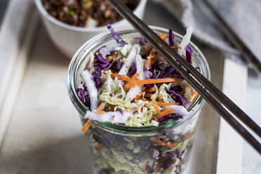 Carrot and cabbage salad in glass jar with metal chopsticks - SBDF04491