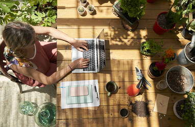 Mature woman using laptop while sitting at table in backyard - VEGF04668