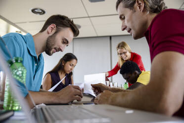 Businessmen working with male and female colleagues in background at office  - BMOF00833