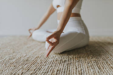 Weibliche Fitness-Trainerin meditiert auf dem Teppich im Yoga-Studio - OCAF00672