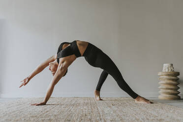 Weiblicher Yogalehrer beugt sich beim Üben im Studio nach hinten - OCAF00680