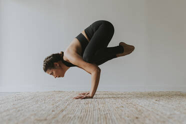 Yogi practicing Kakasana pose in health club - OCAF00681