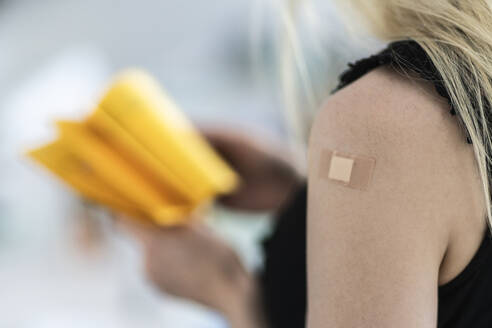 Woman with bandage on arm at vaccination center - CHPF00773