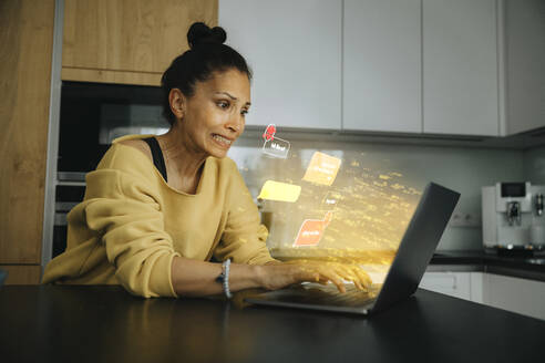 Worried woman using laptop with speech bubble icon at home - LIFIF00050