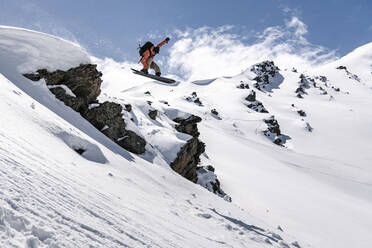 Man snowboarding on snowcapped mountain during vacation - CAVF94217