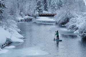 Rückansicht einer Frau beim Paddeln auf einem Fluss im Winter - CAVF94219