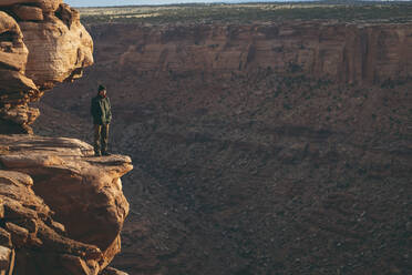 Mann steht am Rande einer Felsklippe im Canyonlands National Park - CAVF94234