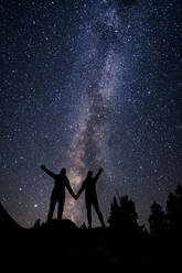 Silhouette Paar hält sich an den Händen, während gegen Sternfeld in der Nacht im Urlaub stehen - CAVF94262