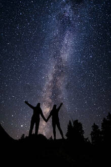 Silhouette couple holding hands while standing against star field at night during vacation - CAVF94262