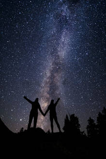 Silhouette Paar hält sich an den Händen, während gegen Sternfeld in der Nacht im Urlaub stehen - CAVF94262