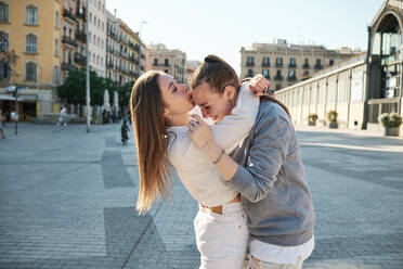 Frau mit Arm um küssende Freundin auf die Stirn in der Stadt stehend - AGOF00146