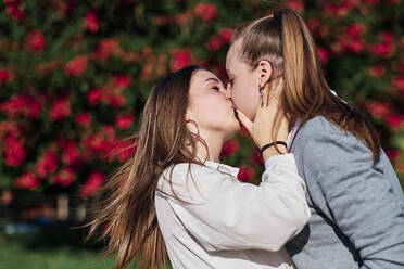 Zärtliches lesbisches Paar, das sich an einem sonnigen Tag küsst - AGOF00150