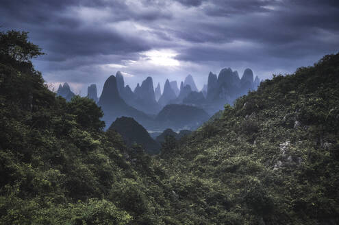 Yangshuo mountains with dark clouds framed by hills, Yangshuo, Guangxi, China, Asia - RHPLF19870