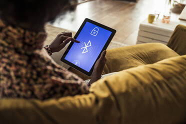 Woman using digital tablet while sitting on sofa - UUF23551