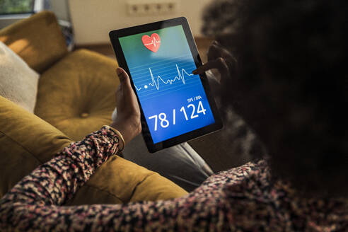 Frau prüft Gesundheitsbericht auf digitalem Tablet zu Hause - UUF23554