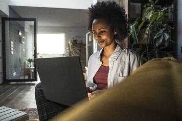 Young female freelancer using laptop while working at home - UUF23569