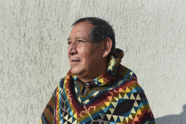 Nachdenklicher Mann trägt traditionellen Poncho an einem sonnigen Tag - DSIF00443