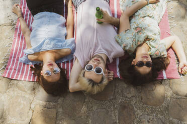 Male and female friends relaxing on blanket during vacations - AFVF08953