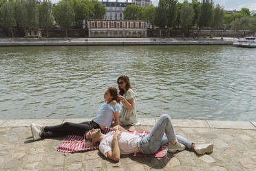 Frau bindet die Haare ihrer Freundin an einen schwulen Mann, der sich an einem sonnigen Tag entspannt - AFVF08964
