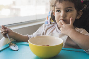 Kleinkind isst Müsli auf dem Hochstuhl zu Hause - DSIF00459