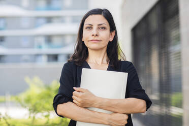 Confident businesswoman with file standing at office park - SGF02824