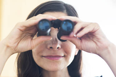 Female professional looking through binoculars in office - SGF02837