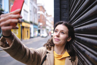 Frau nimmt Selfie durch Smartphone bei geschlossenem Shutter - ASGF00618