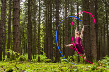 Lächelnde Turnerin bei rhythmischer Gymnastik mit Bändern im Wald - STSF02977