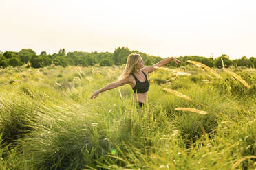 Mature woman with arms outstretched dancing on meadow - DLTSF01955