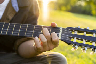 Junger Mann spielt Gitarre im Park - AFVF08988