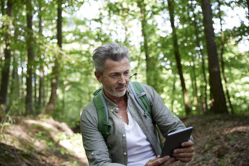 Männlicher Wanderer mit digitalem Tablet im Wald - FMKF07196