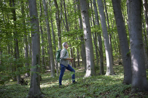 Männlicher Rucksacktourist beim Wandern inmitten von Bäumen im Wald - FMKF07199