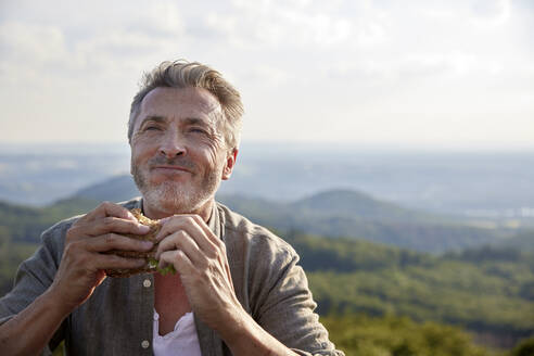 Man smiling while holding sandwich - FMKF07224