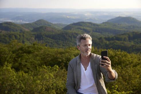 Älterer Mann nimmt Selfie durch Smartphone - FMKF07228