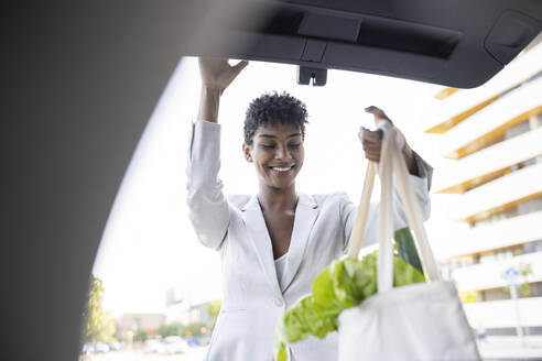 Female professional loading groceries in car trunk - JCCMF02924