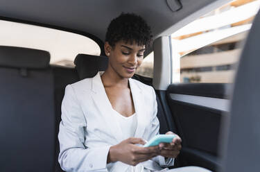 Businesswoman using smart phone while sitting in car - JCCMF02925