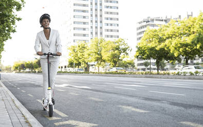Happy weiblichen Pendler Reiten elektrische Push-Roller auf der Straße in der Stadt - JCCMF02932